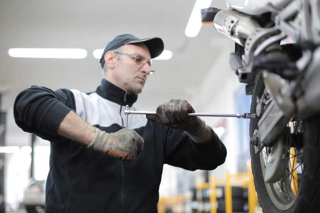 Man skillfully fixes a motorcycle tire using a wrench in an indoor workshop setting.